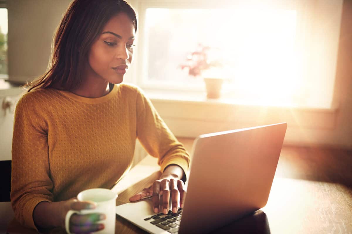 Woman checking her computer and holding coffee cup